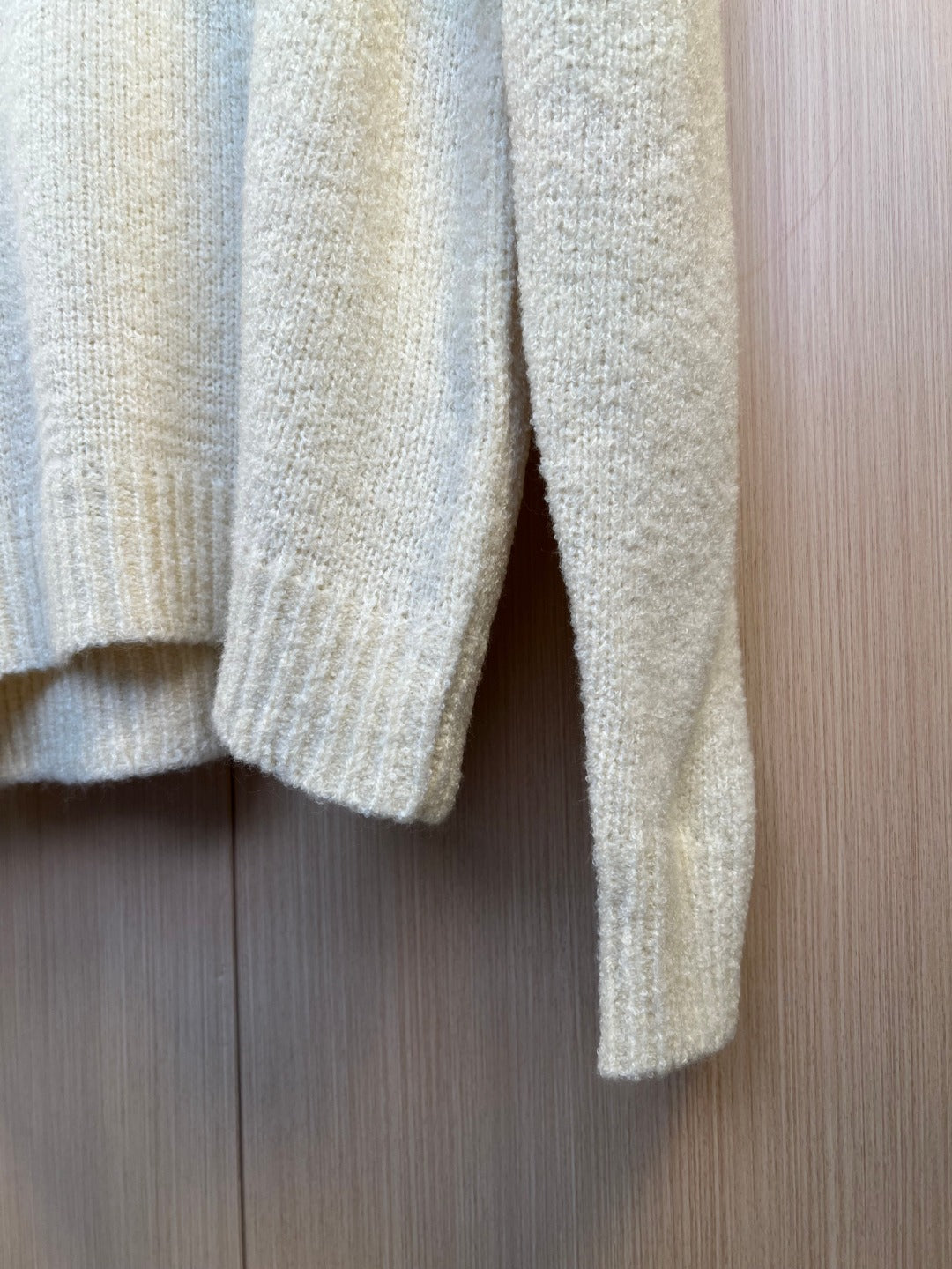 Light cream knit sweater sleeves and hem with ribbed cuffs, close-up