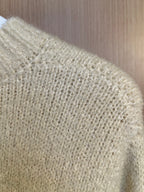 Light cream textured knit fabric of a sweater, close-up of shoulder and knit pattern