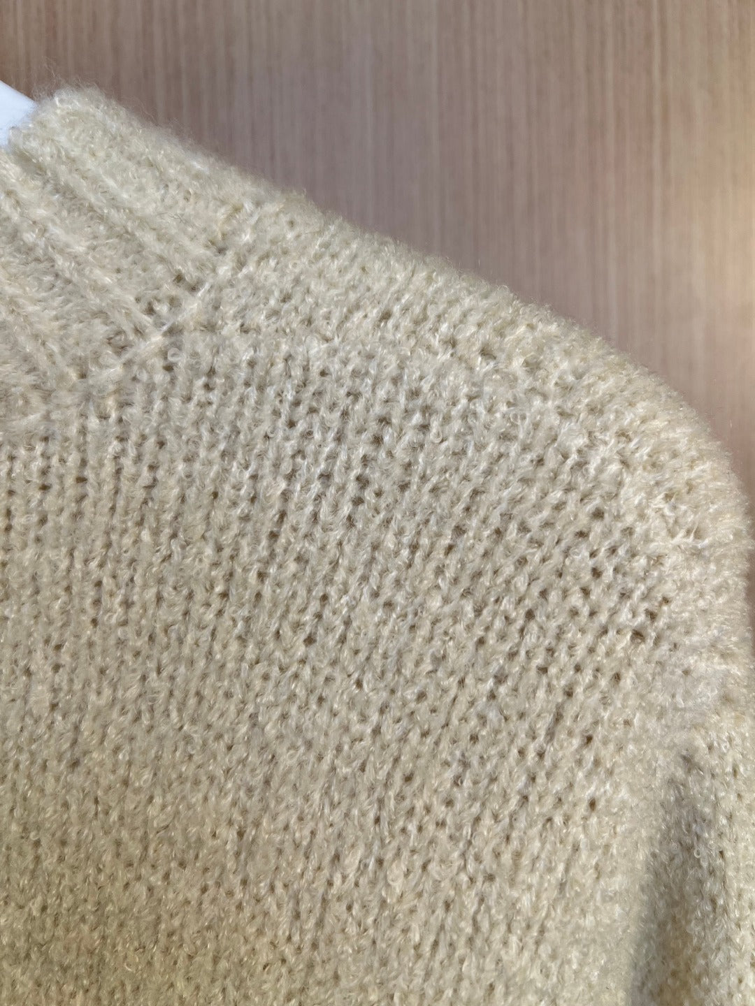 Light cream textured knit fabric of a sweater, close-up of shoulder and knit pattern