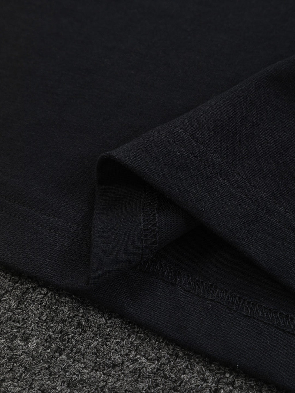 Close-up of black T-shirt hem with stitched edge and fabric texture
