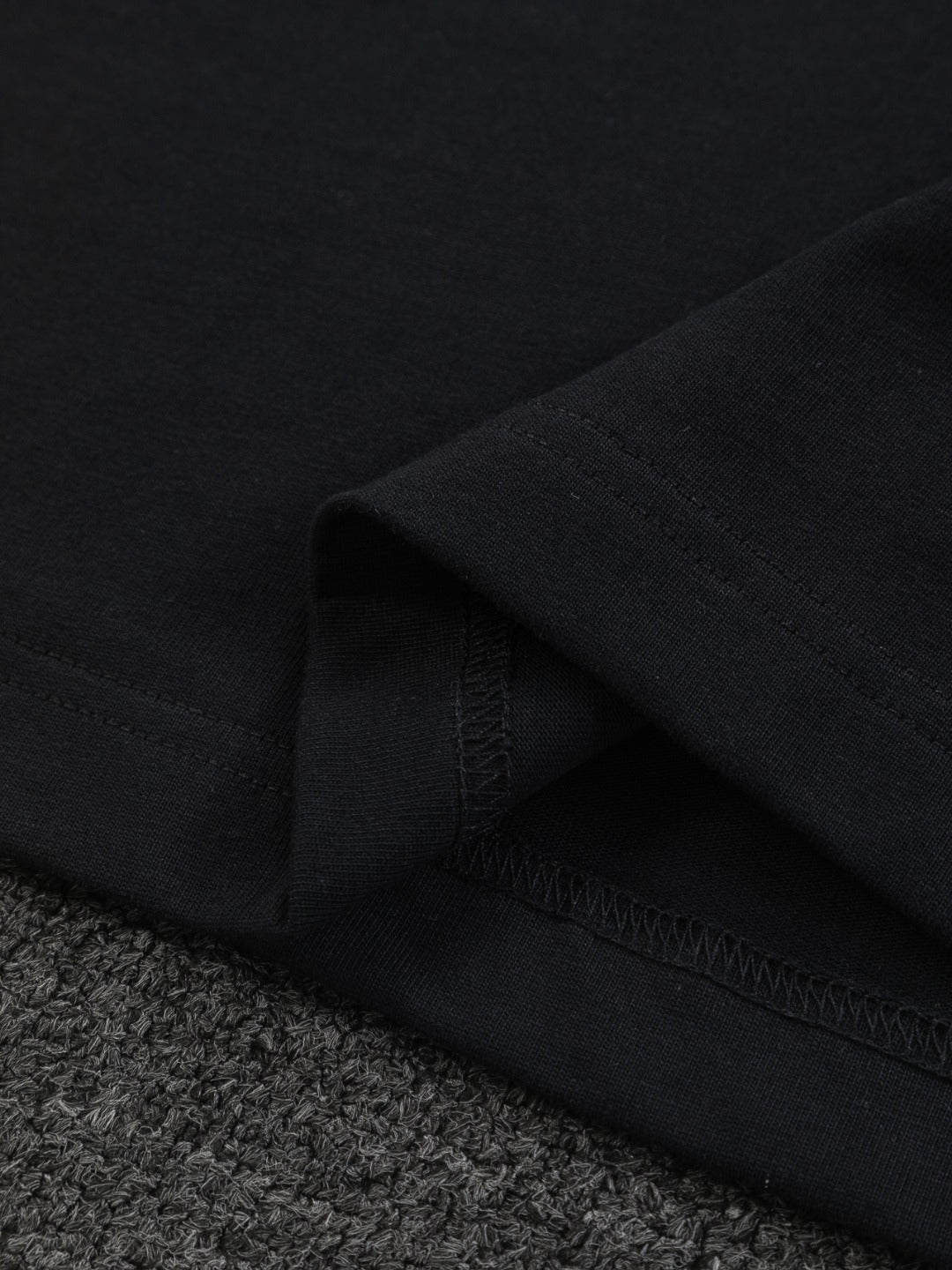 Close-up of black T-shirt hem with stitched edge and fabric texture