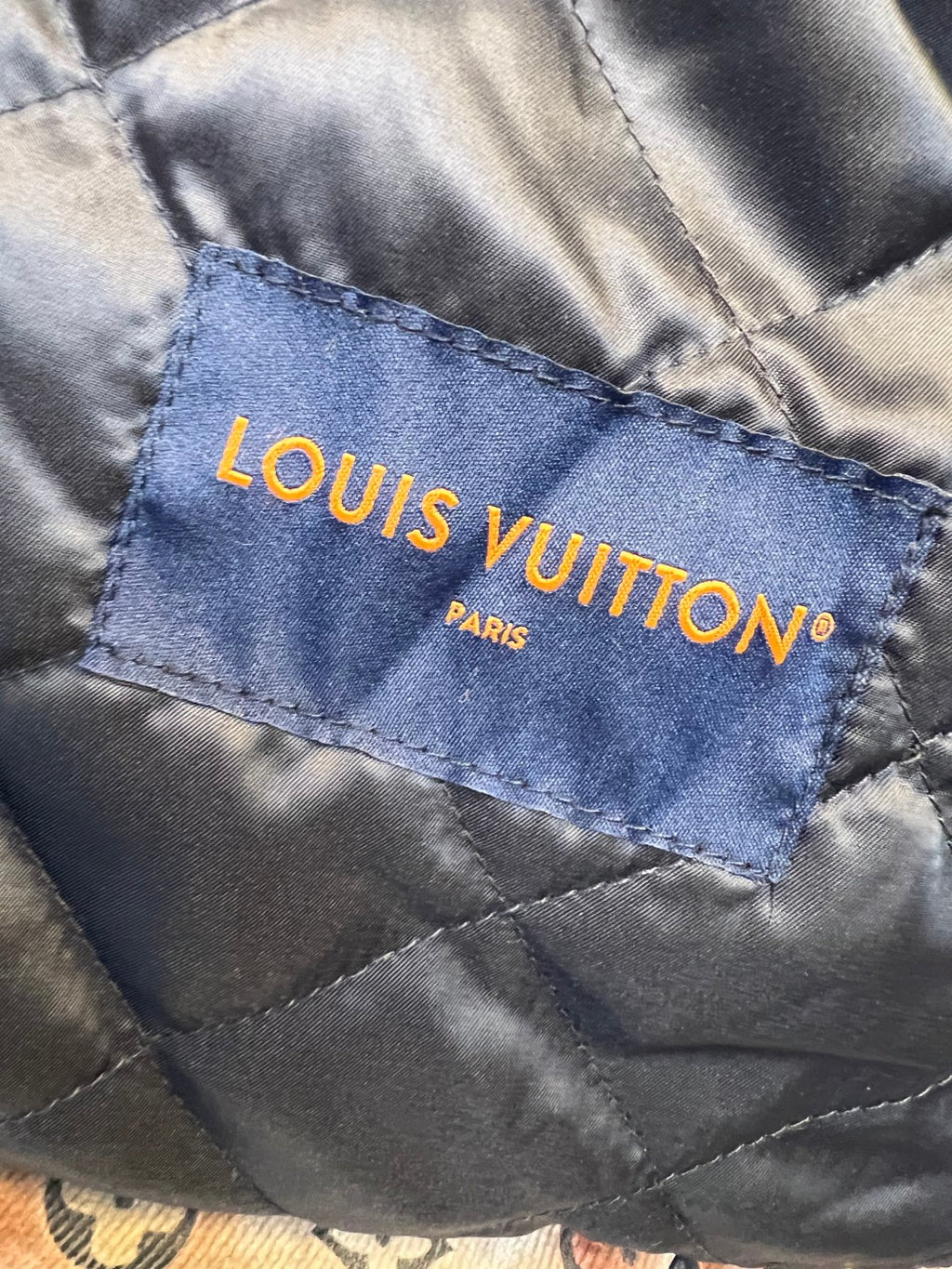 Louis Vuitton branded inner fabric label in blue with orange lettering
