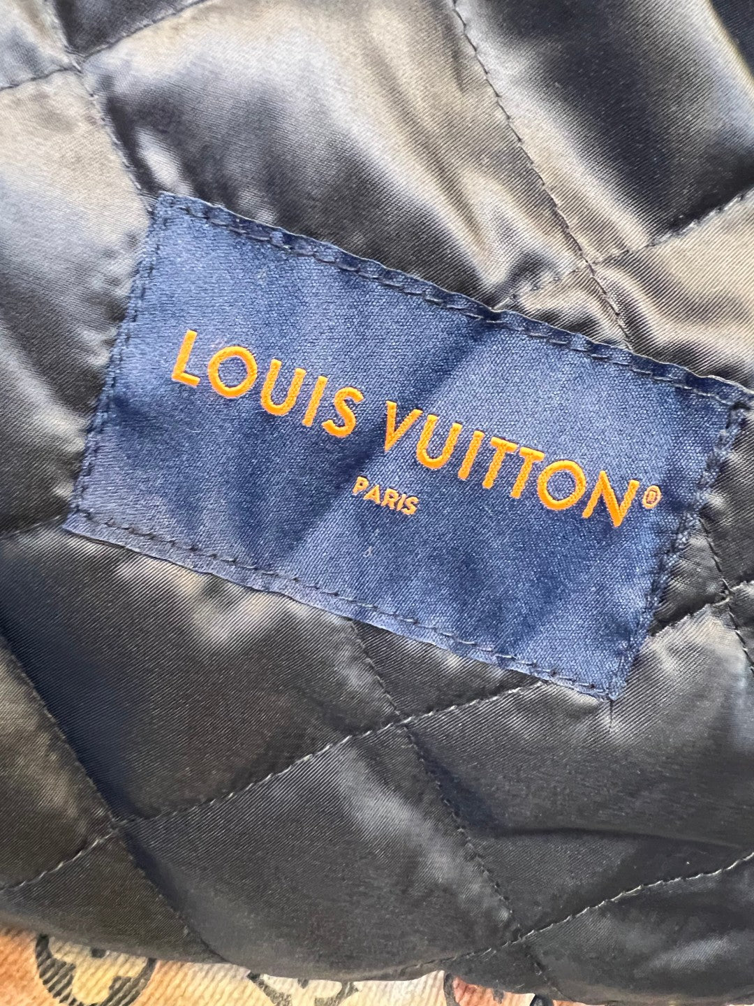 Louis Vuitton branded inner fabric label in blue with orange lettering