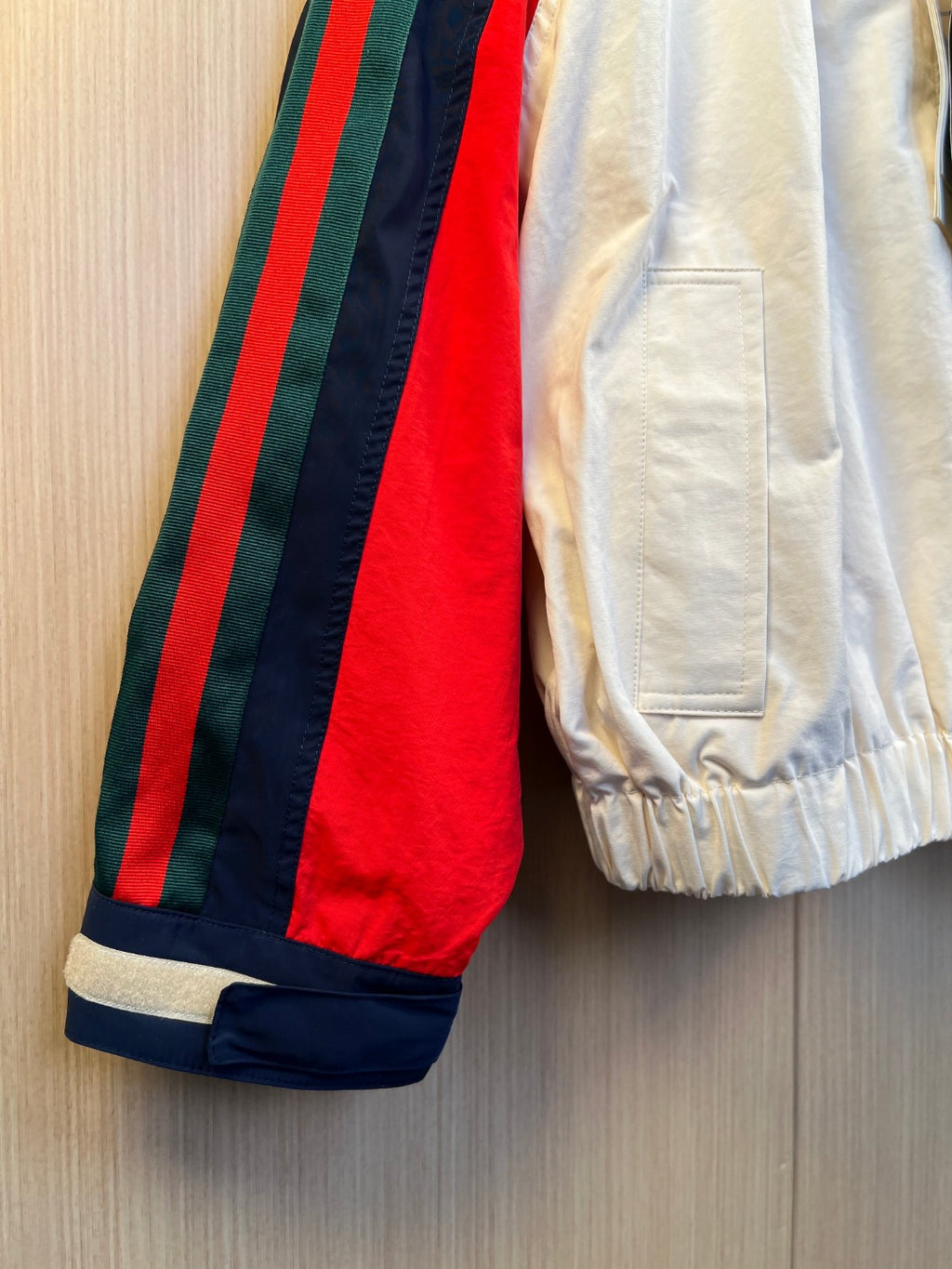 White jacket sleeve with elastic cuff; red, navy, and green stripe side panel
