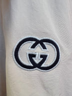 Embroidered logo on light fabric with dark outline and interlocking pattern