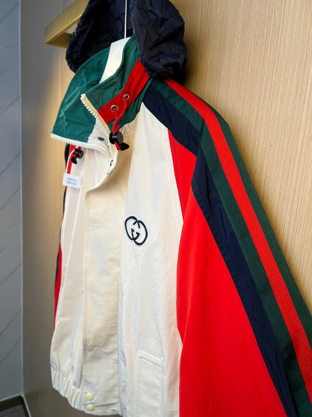 Striped hooded jacket in white with red, navy, and green accents, front zipper