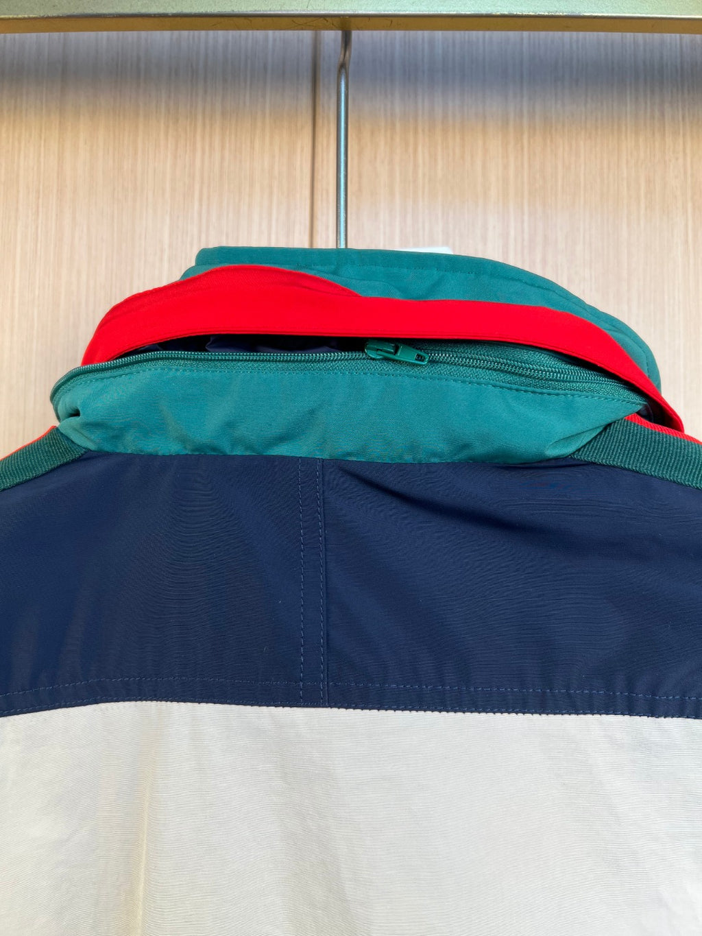 Close-up of hood seam and zipper area on colorblock jacket with teal and red trim