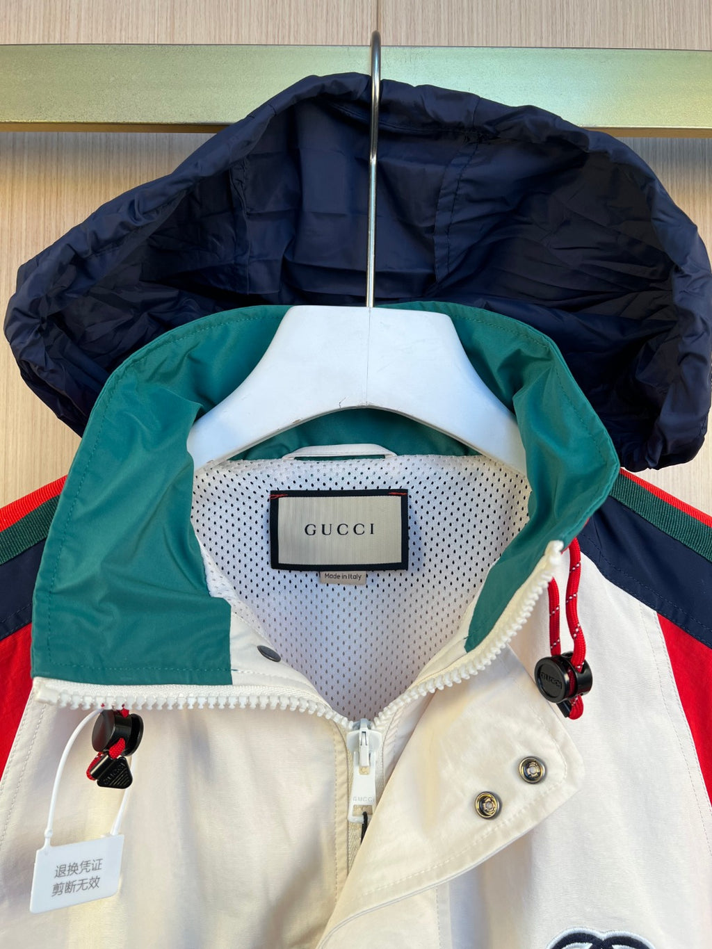 Gucci label on white hooded jacket neckline with green lining and navy hood