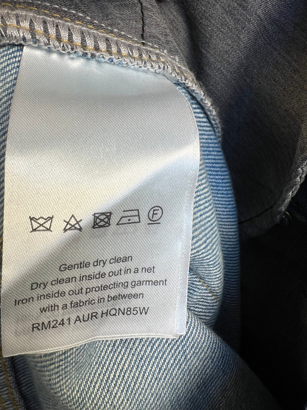 Blue monogram denim pants care label with washing symbols and dry-clean text