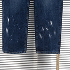 Pair of dark blue denim jeans with uneven wash and distressed speckled patches