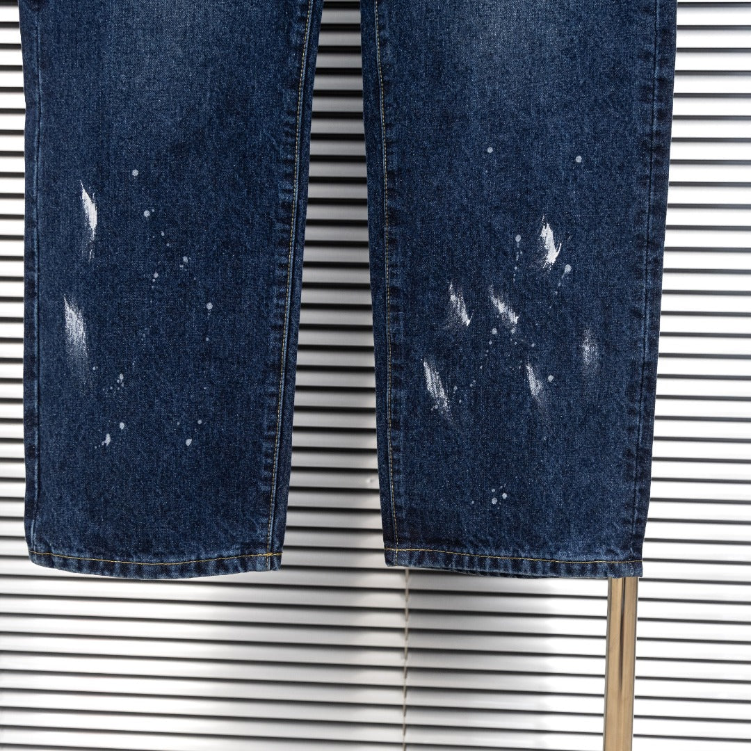Pair of dark blue denim jeans with uneven wash and distressed speckled patches