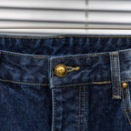 Denim pants waistband detail with gold button and stitched center seam