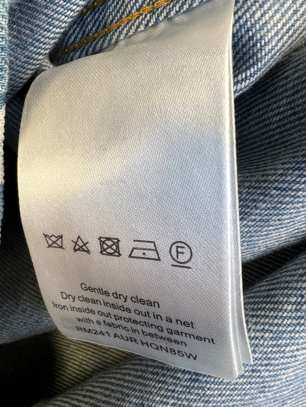 Clothing care label inside Louis Vuitton denim shirt with wash icons and instructions