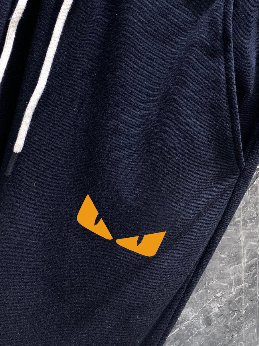 Navy track pants with small yellow logo graphic on thigh