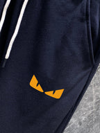 Navy track pants with small yellow logo graphic on thigh