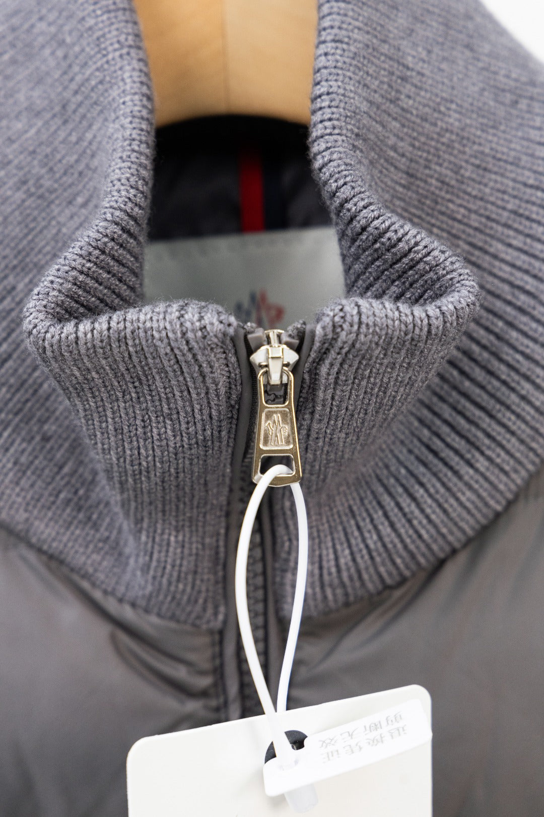 Moncler puffer jacket close-up of zip pull and gray ribbed knit collar