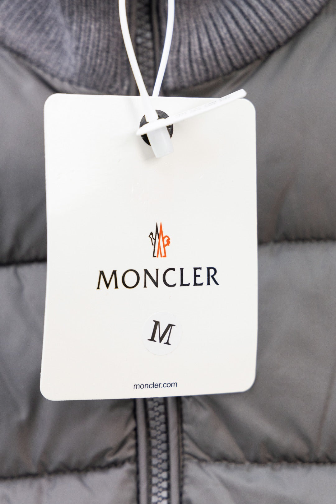 Moncler size tag on gray puffer jacket front zipper