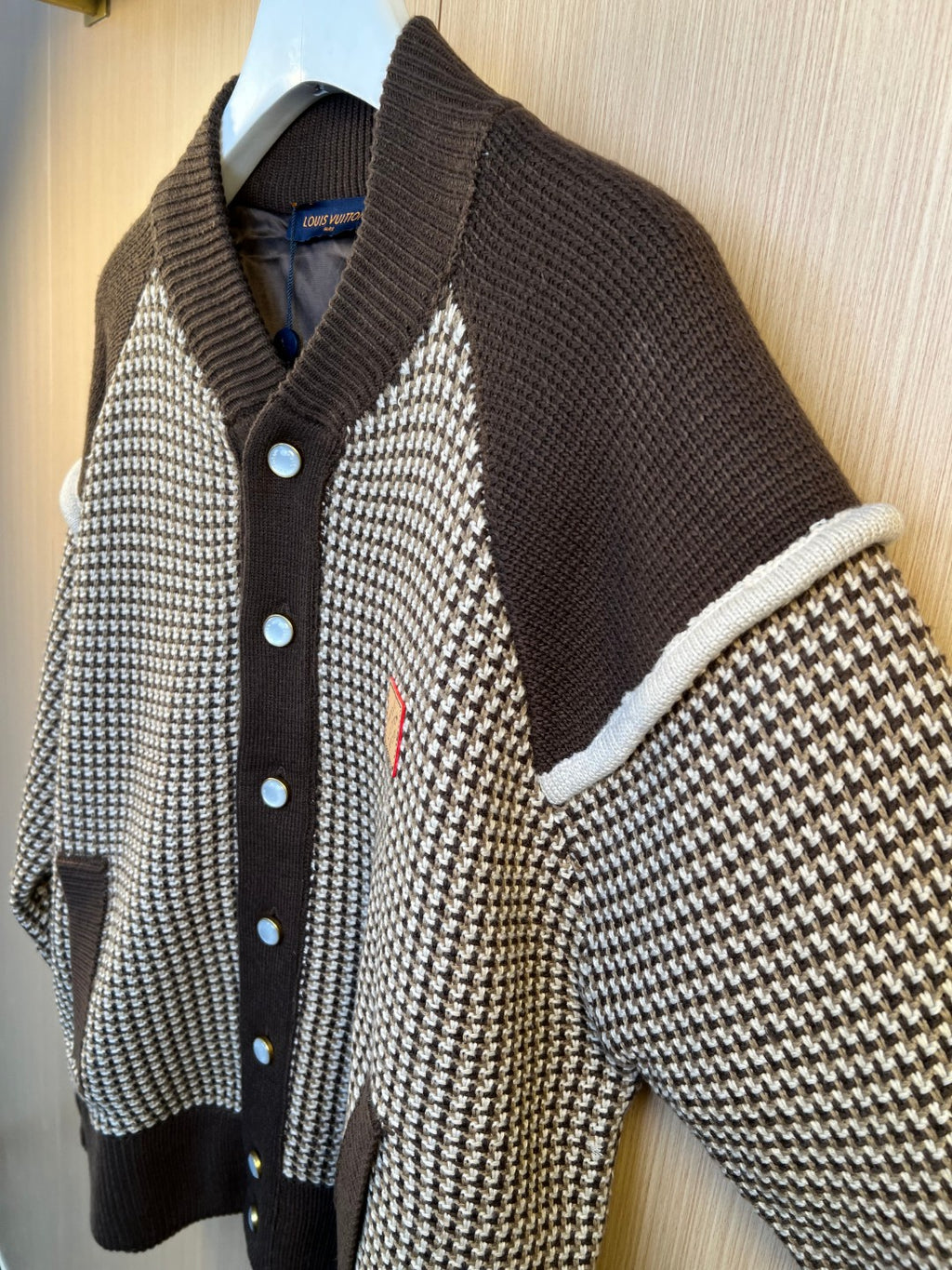Two-tone knit cardigan with houndstooth panels, dark button placket, and blue buttons