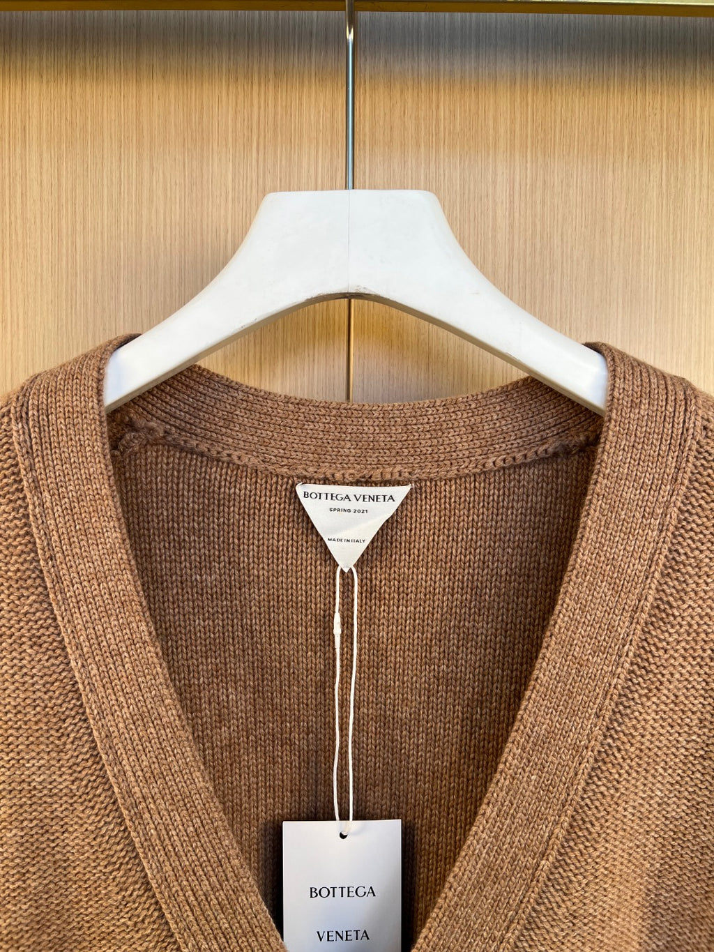 Brown knit cardigan neckline with brand tag on white hang tag