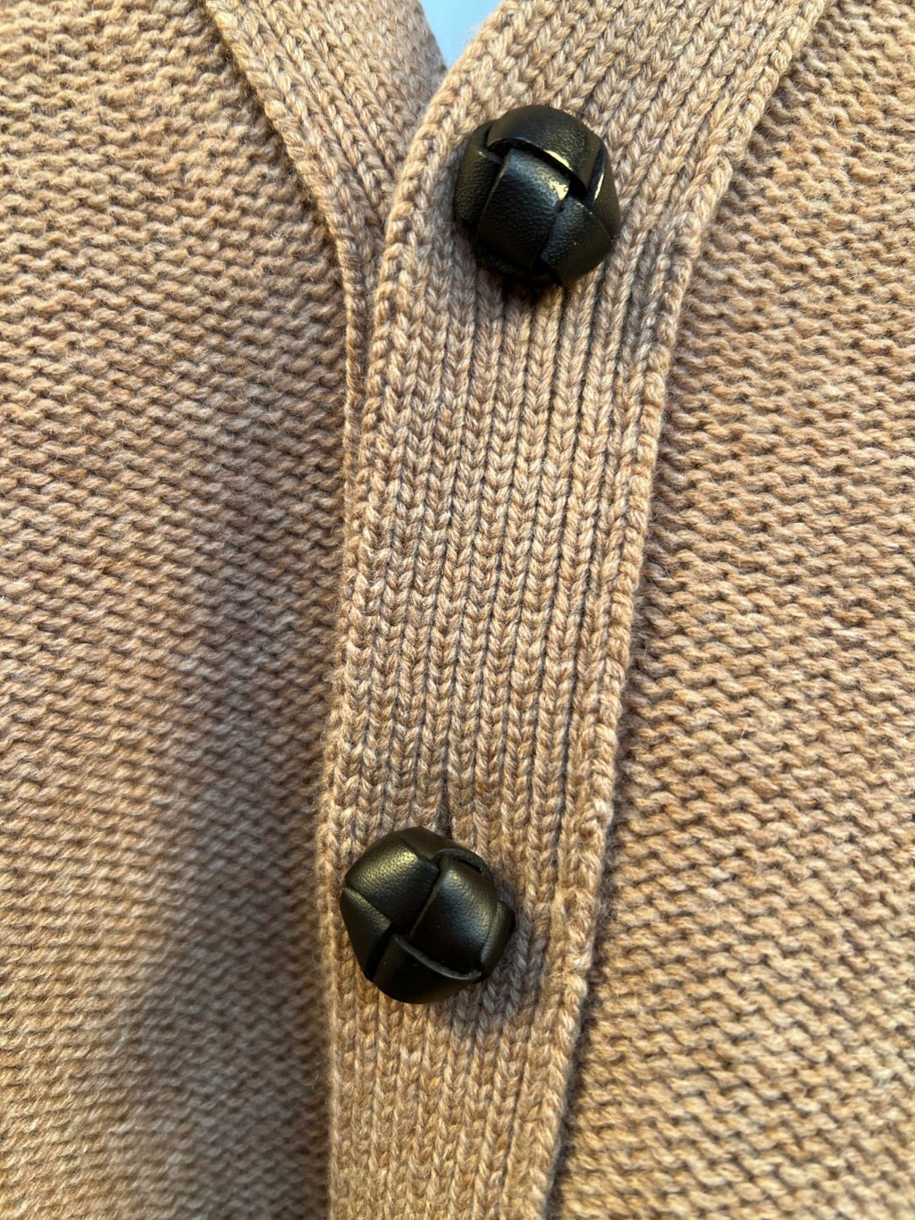 Brown knit cardigan button placket with two black button accents