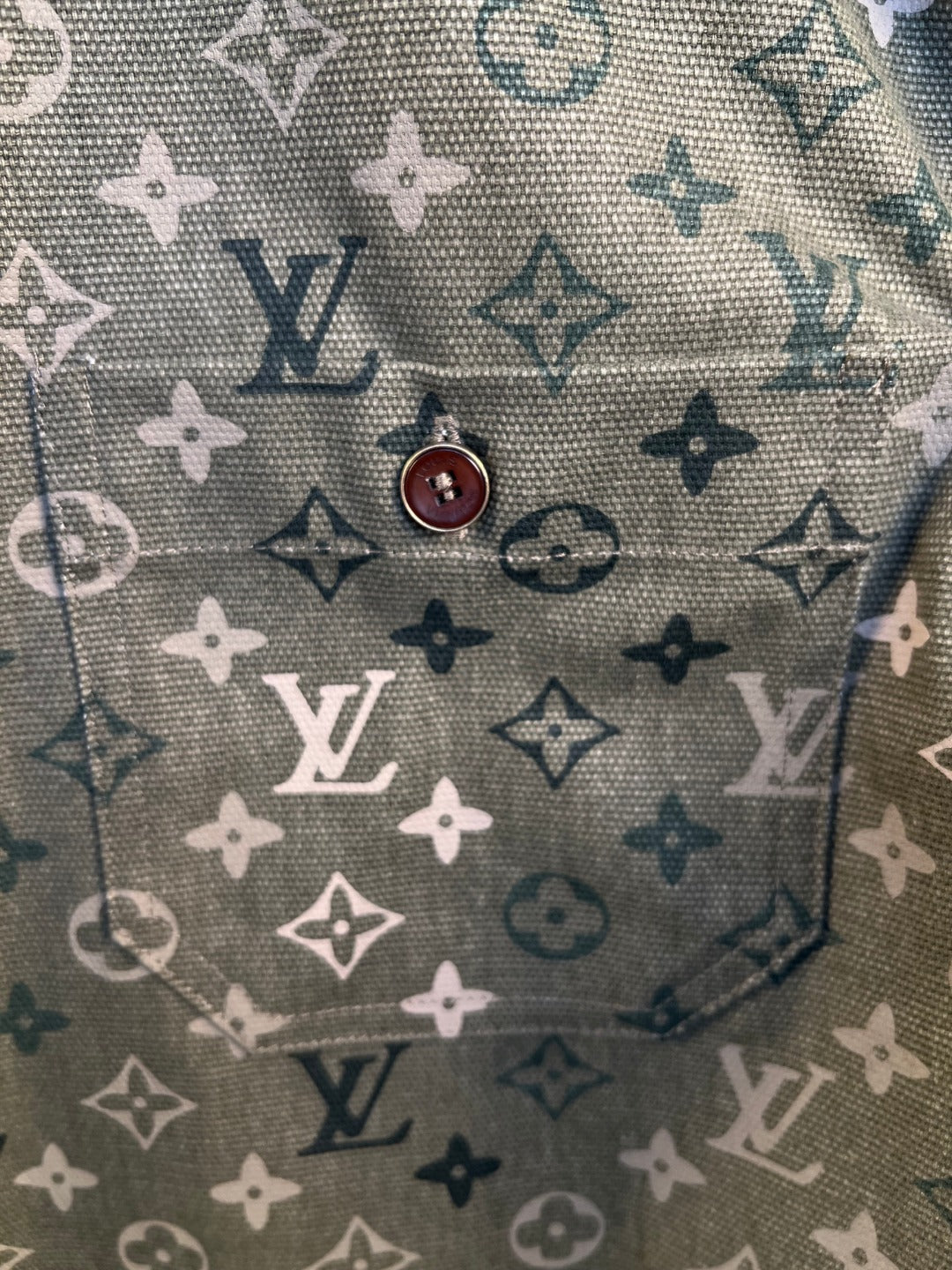 Close-up of dark green monogram-pattern shirt fabric with contrast icons