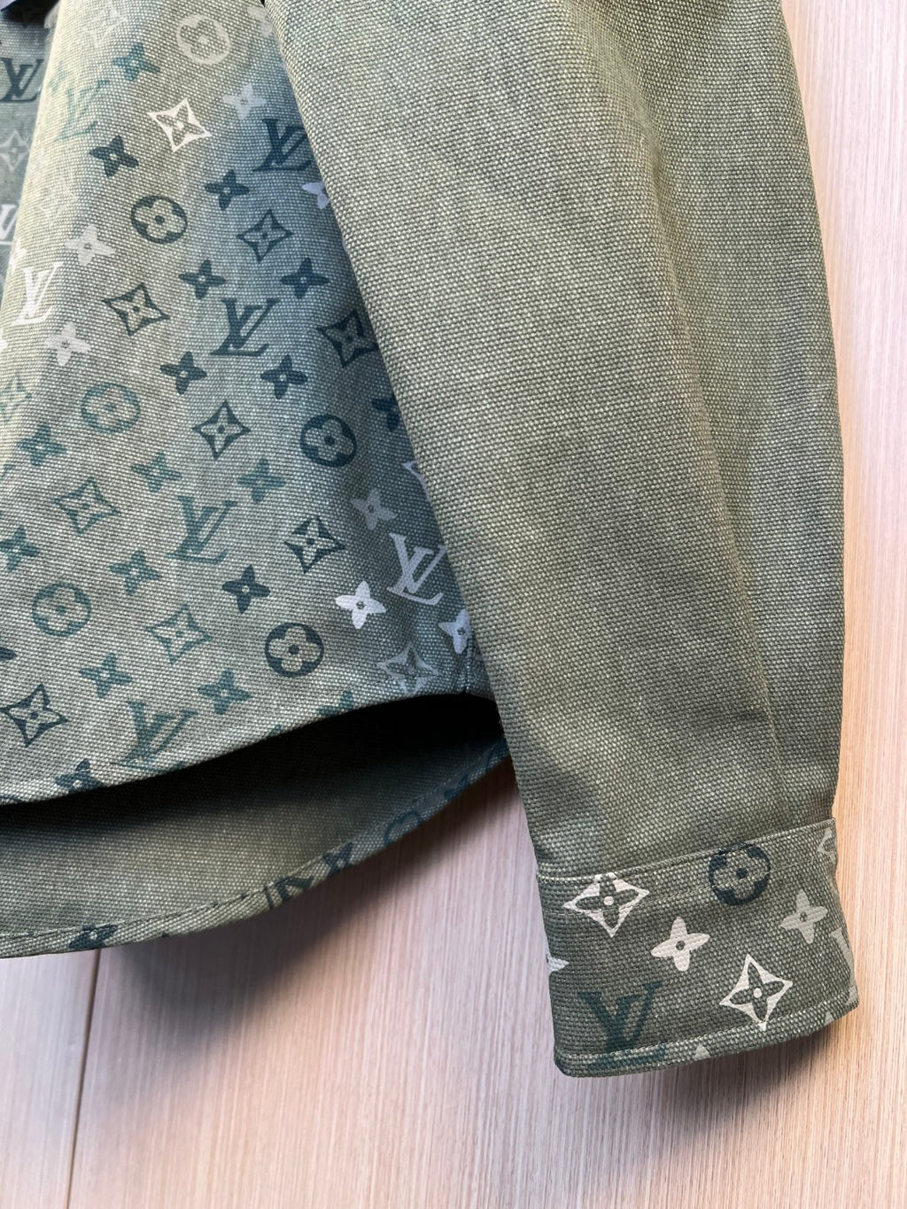 Shirt cuff and sleeve end in dark green with repeating monogram pattern
