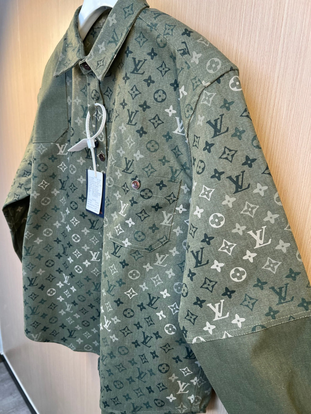 Long-sleeve button-up shirt in dark green monogram print with attached hang tag