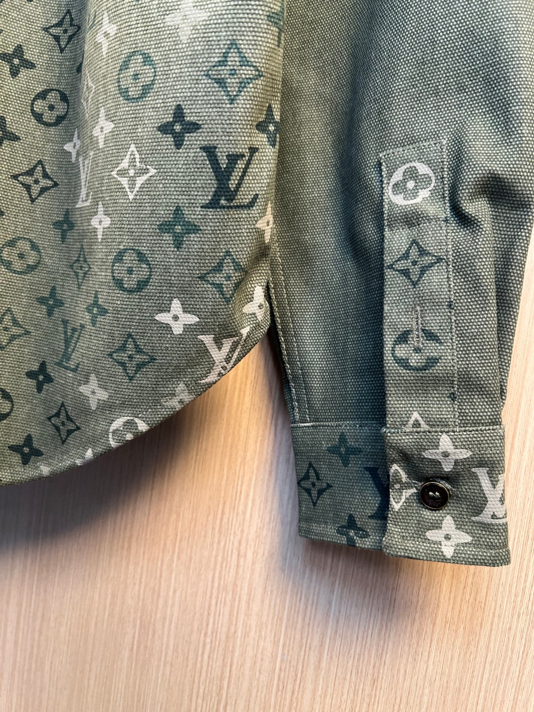 Close-up of shirt cuff and sleeve seam in dark green monogram pattern