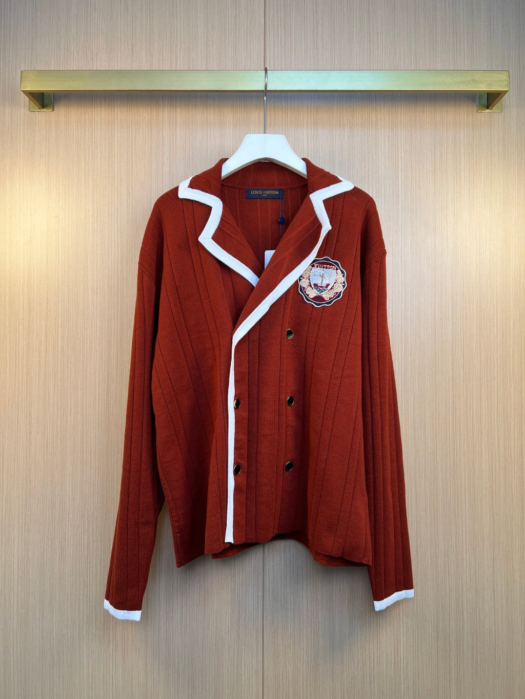 Rust red long-sleeve knit cardigan with white striped trim and embroidered crest