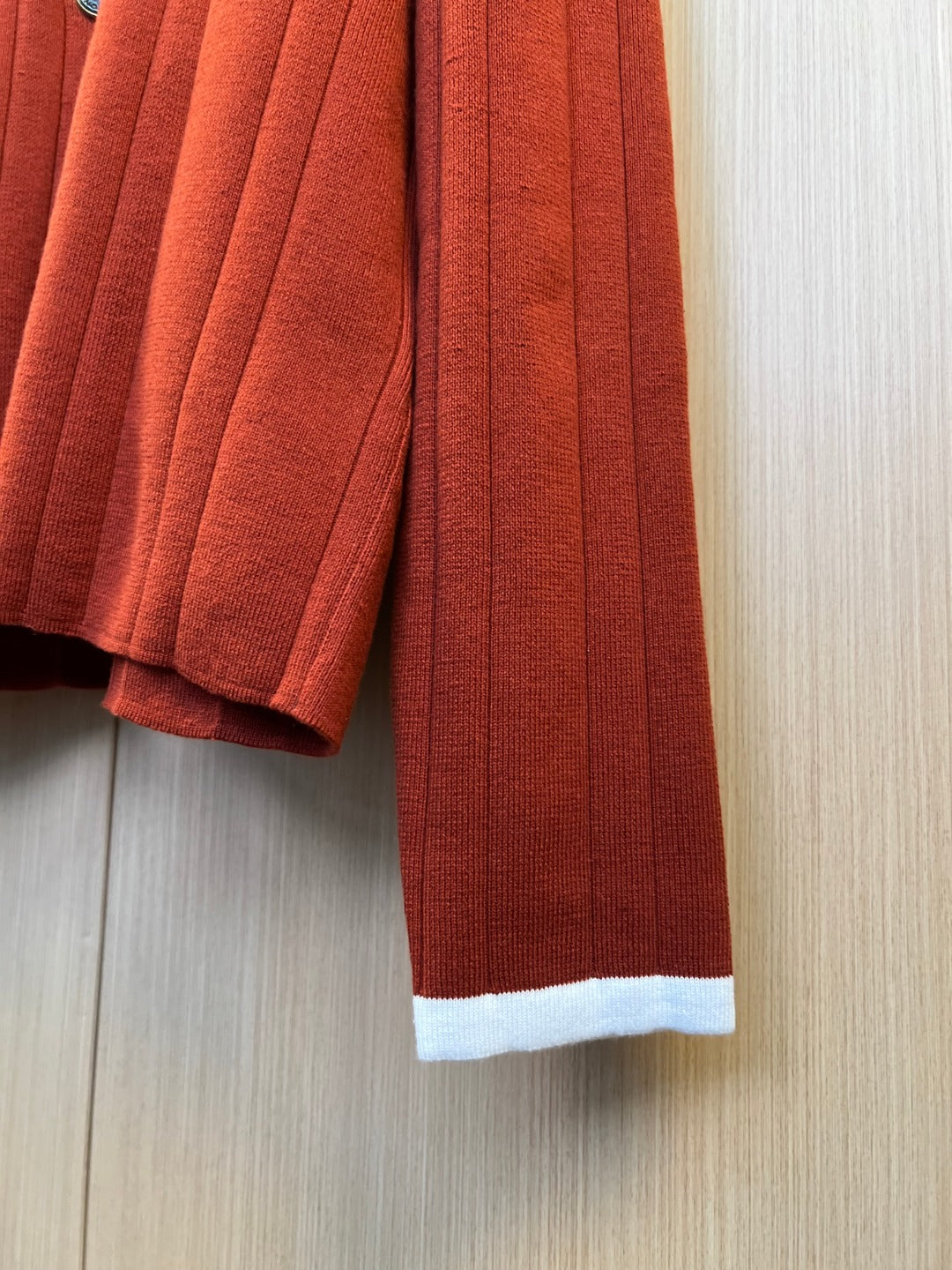 Rust red knit cardigan sleeve and hem with ribbed white cuff trim
