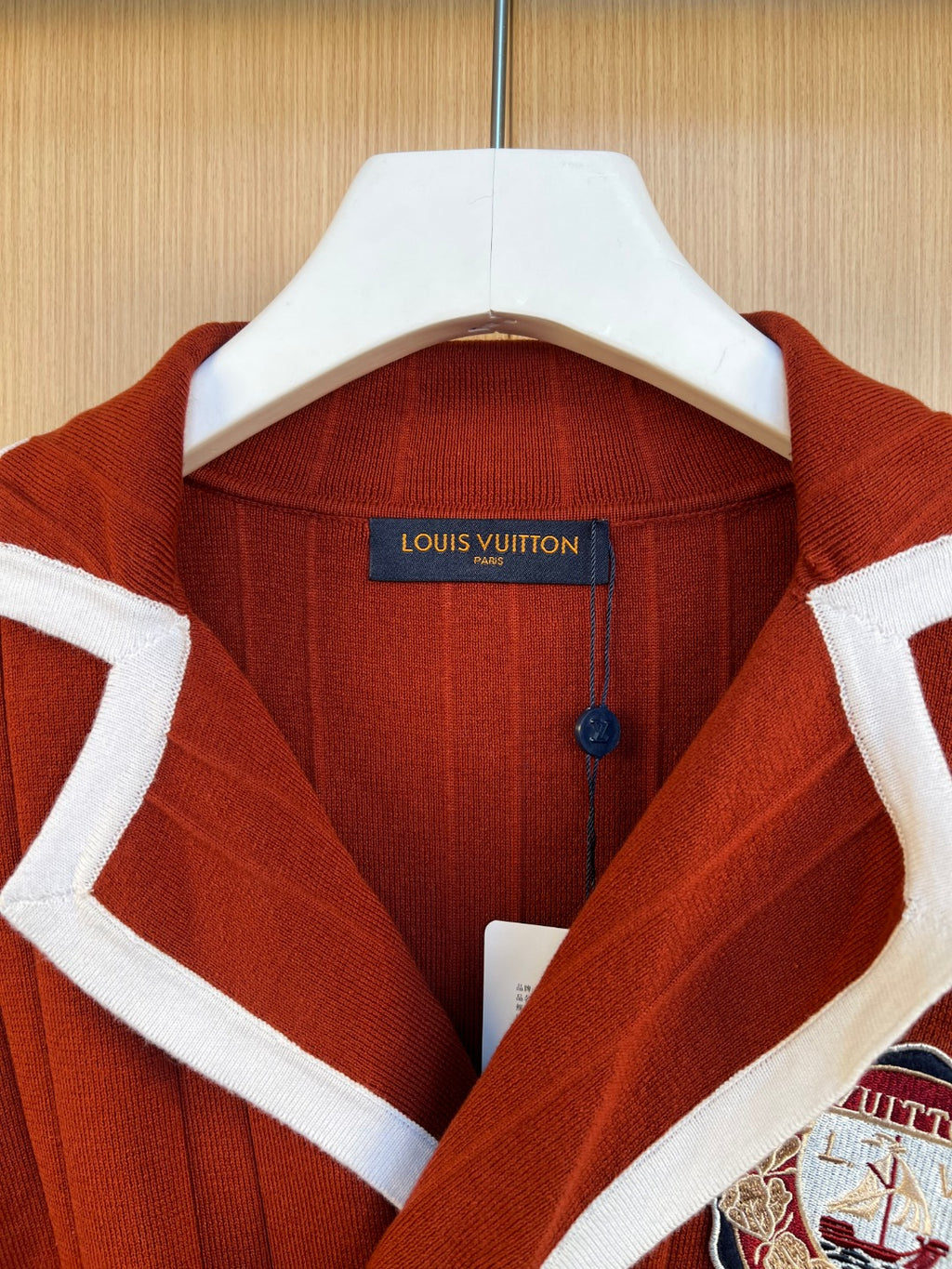 Rust red knit cardigan with white collar trim and Louis Vuitton neck label