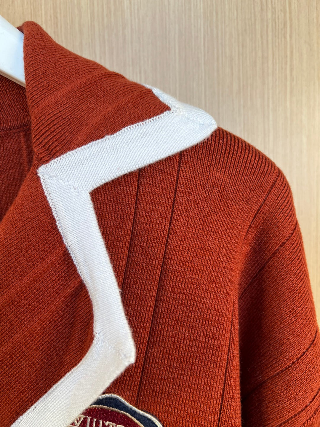 Rust red knit cardigan shoulder seam with white ribbed trim