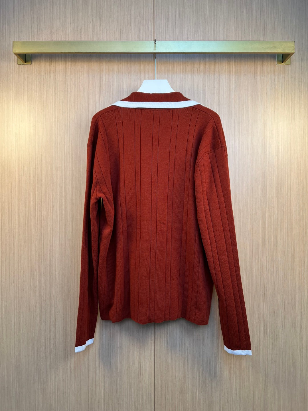 Rust red long-sleeve cardigan with ribbed back texture and white hem trim