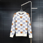 White knit sweater with blue GG motif and orange teddy bear designs.