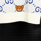 White knit sweater front hem with orange teddy bear face and blue dotted GG pattern.
