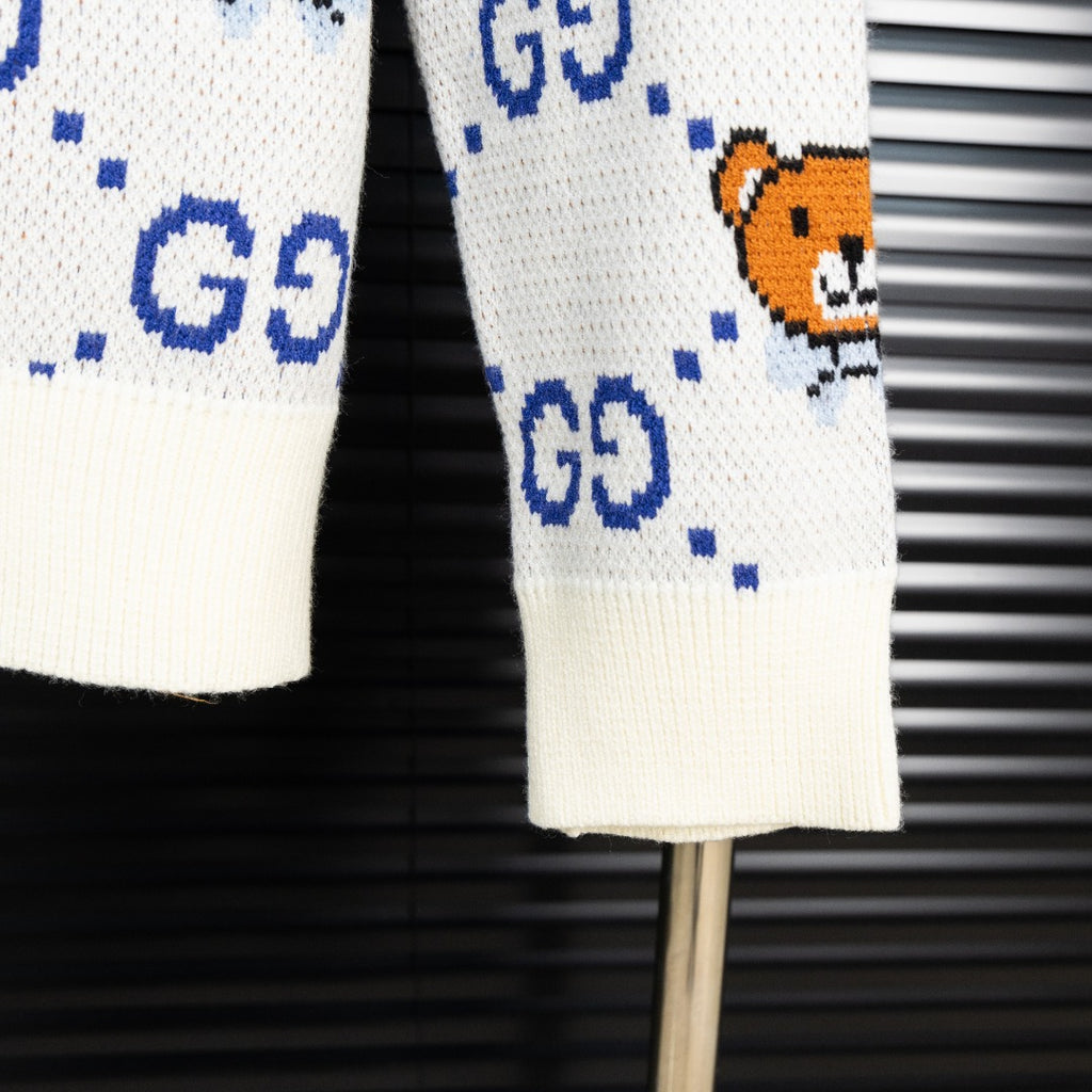 White knit sweater hem with blue dotted GG motif and small orange teddy bear graphic.