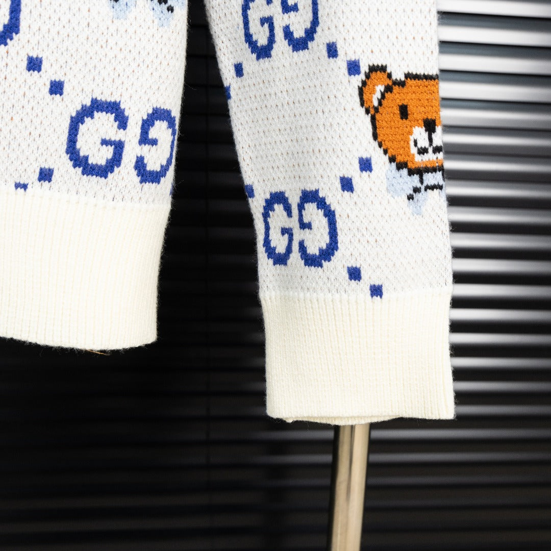 White knit sweater hem with blue dotted GG motif and small orange teddy bear graphic.