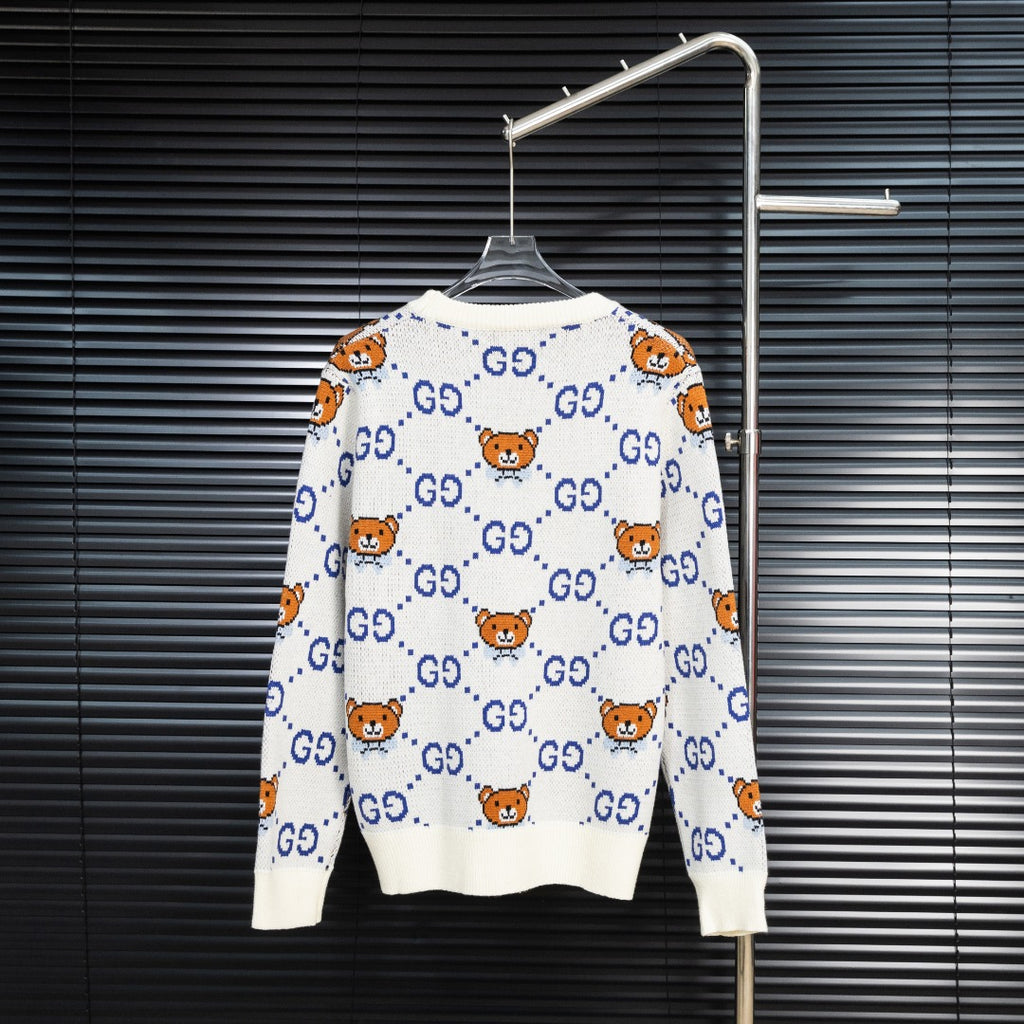 White knit sweater with blue GG motifs and orange teddy bear pattern, back view.