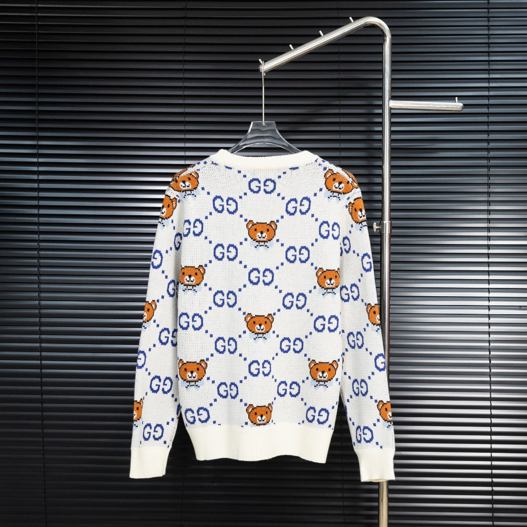 White knit sweater with blue GG motifs and orange teddy bear pattern, back view.