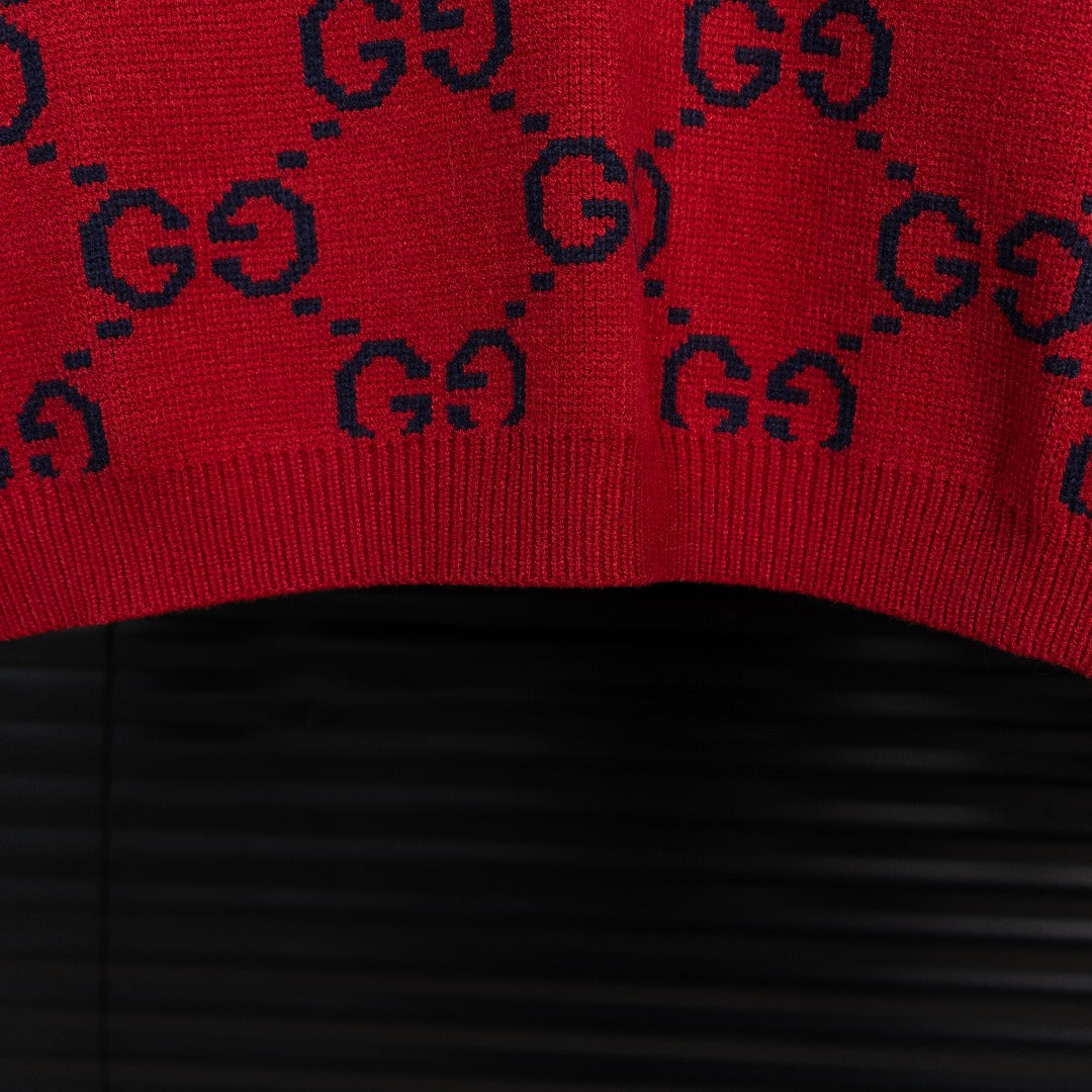 Bottom hem of navy knit sweater with red GG monogram pattern and ribbed edge.