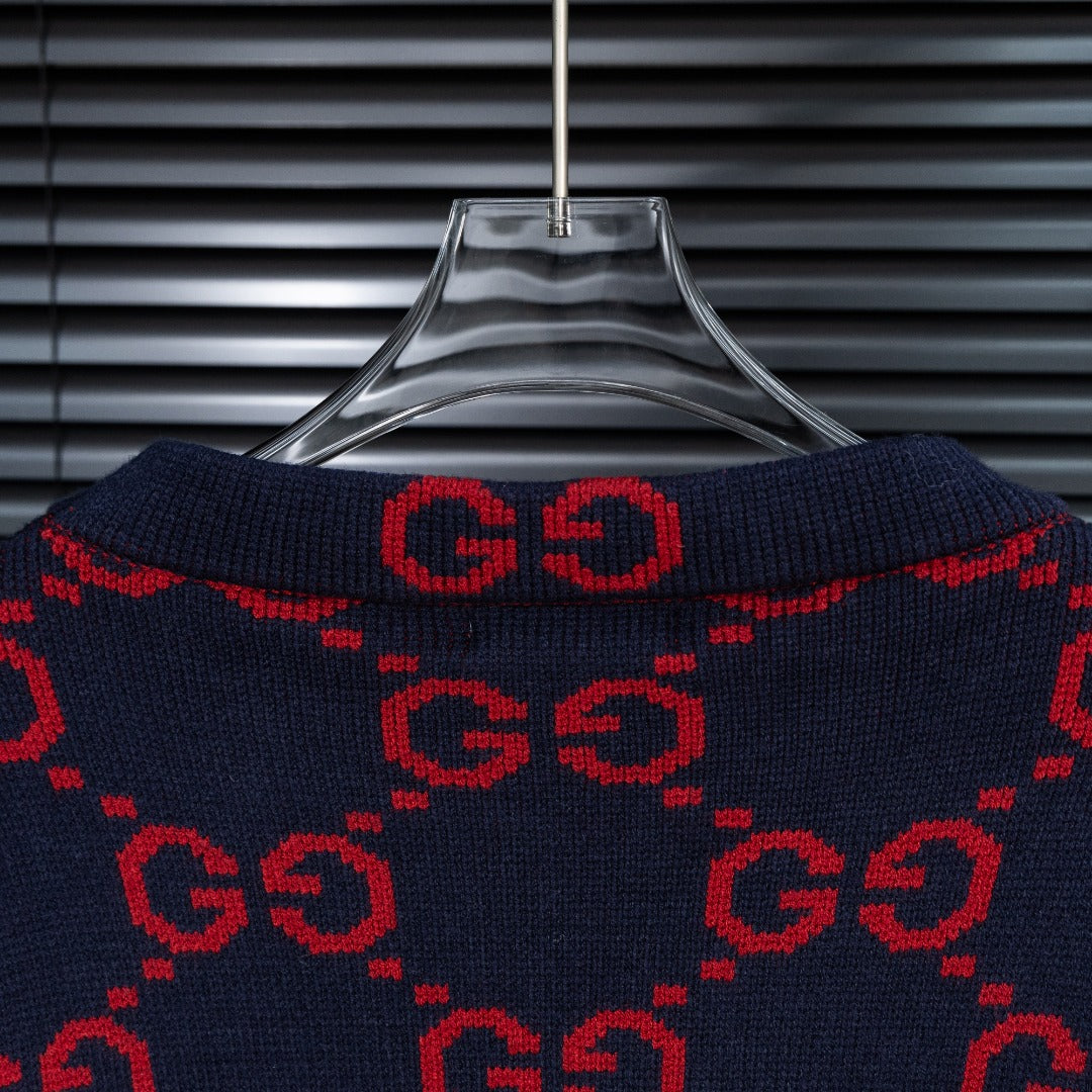 Navy crew neck knit sweater with red GG monogram pattern, shown on hanger.