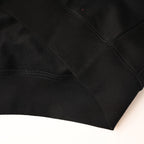 Black hoodie lower hem with ribbed cuff detail and stitched corner.