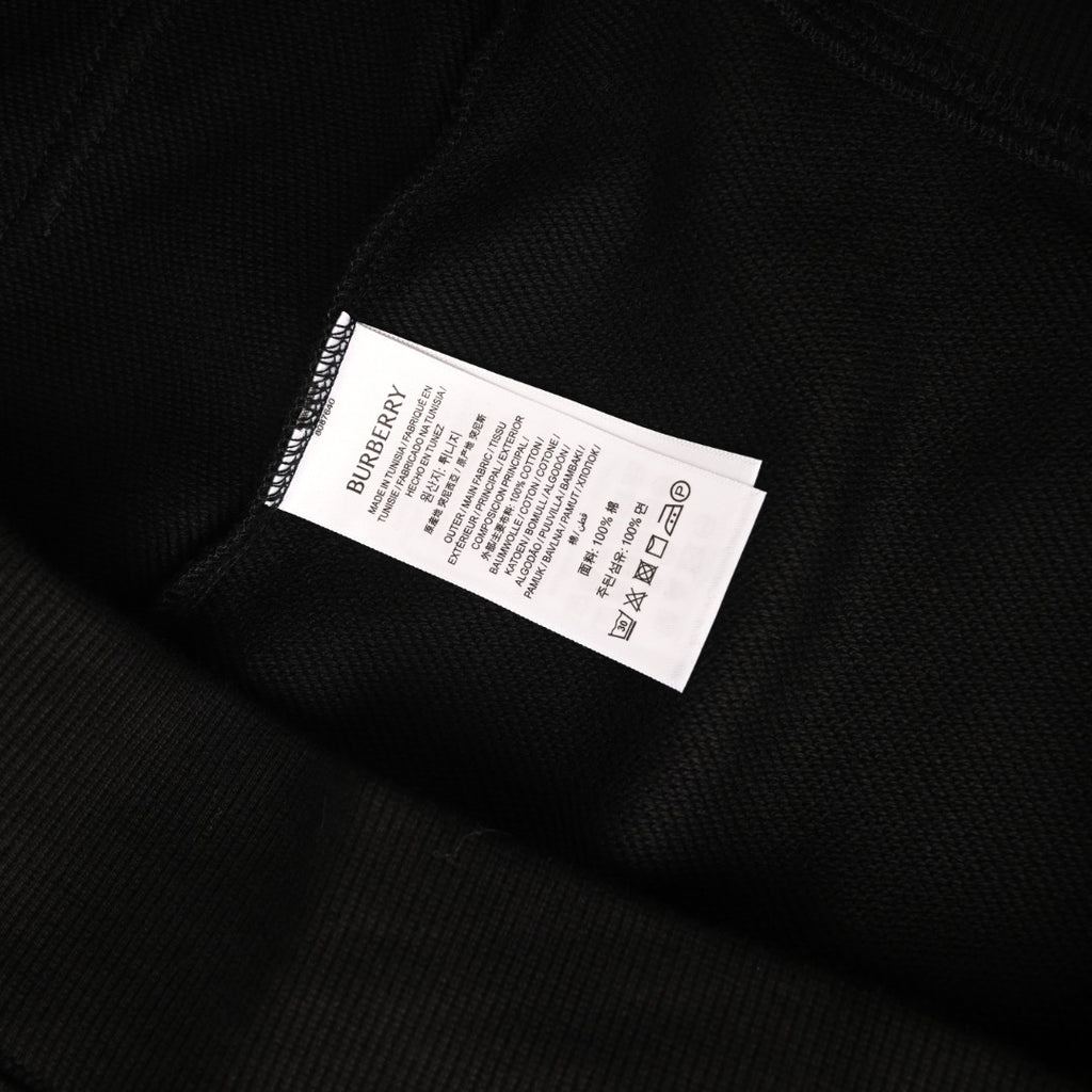 Black hoodie care label tag with BURBERRY branding and symbols.
