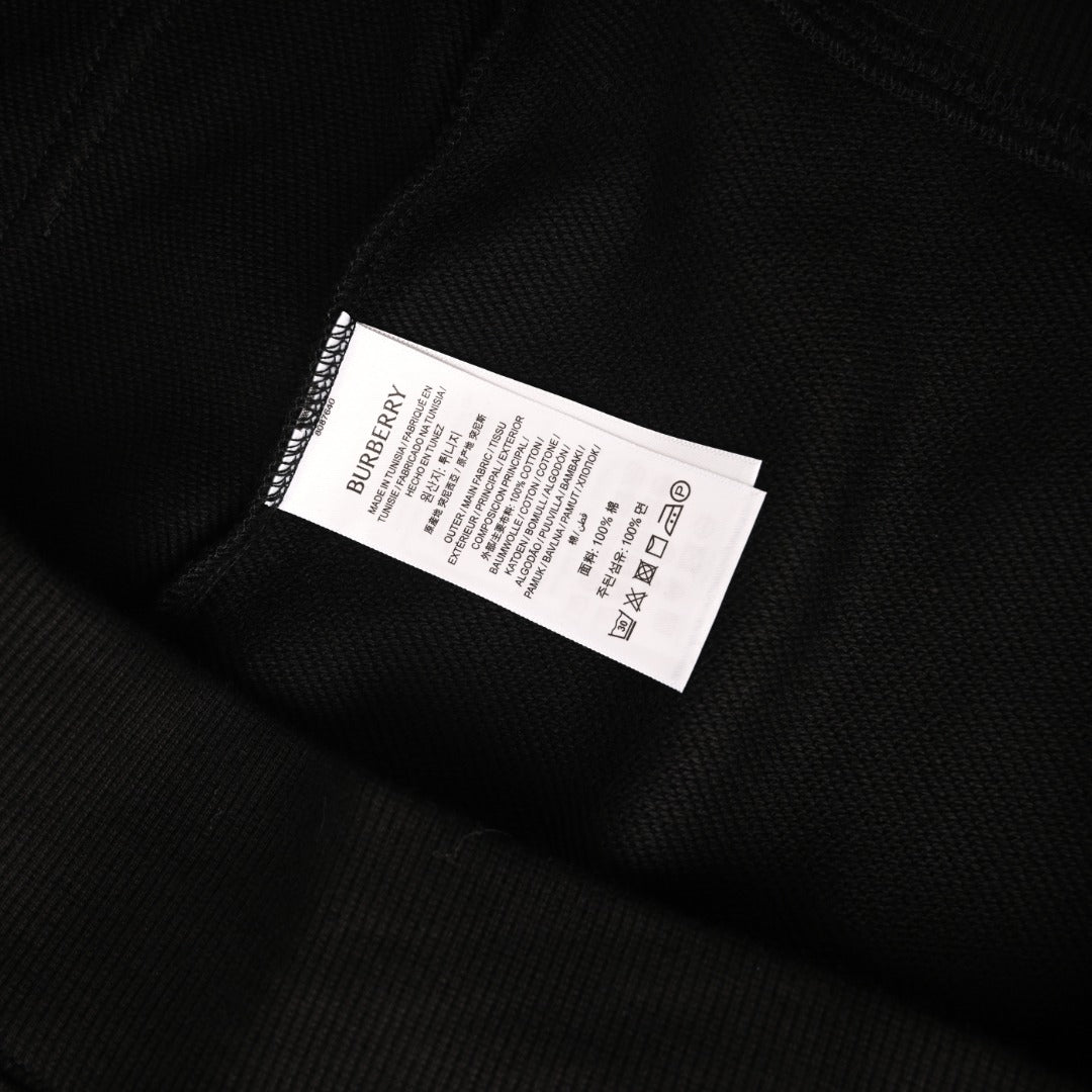 Black hoodie care label tag with BURBERRY branding and symbols.