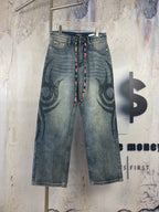 Blue denim pants with large black graffiti print and multicolor drawstring waist