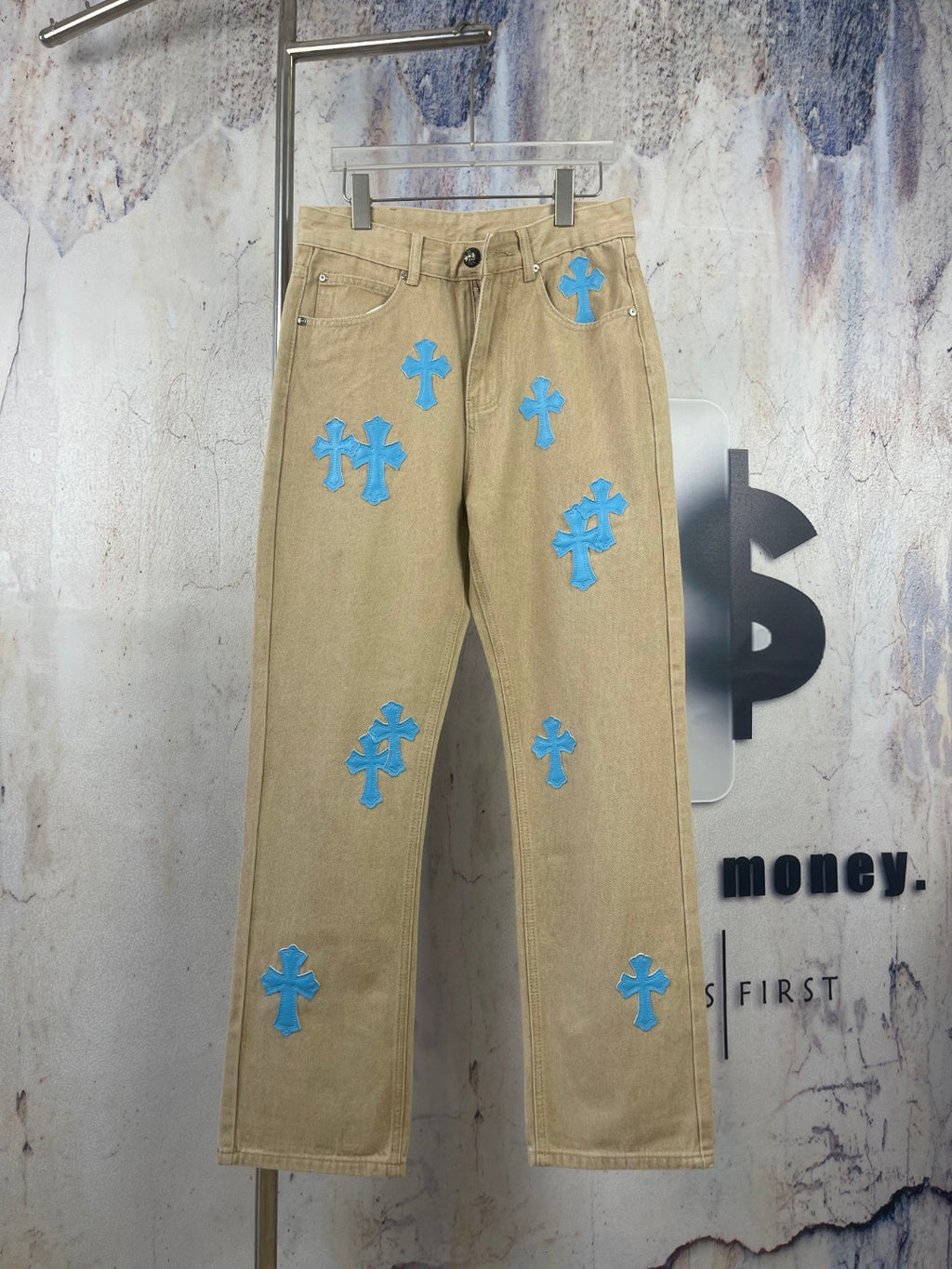 Tan pants with blue cross-heart patches, front button fly and side pockets