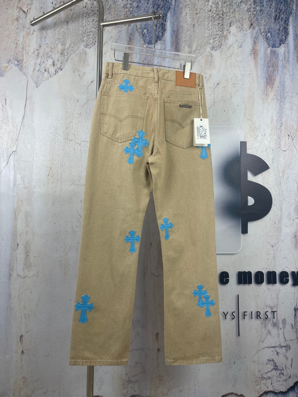 Beige pants with scattered blue cross-heart patches, zip fly and belt loops
