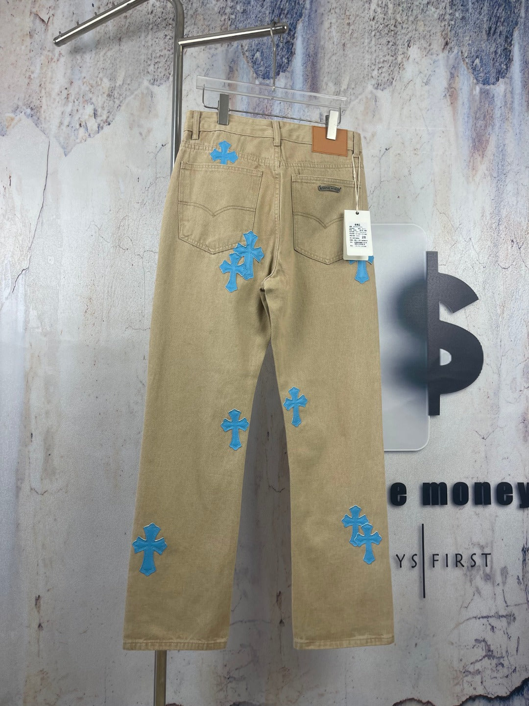 Beige pants with scattered blue cross-heart patches, zip fly and belt loops