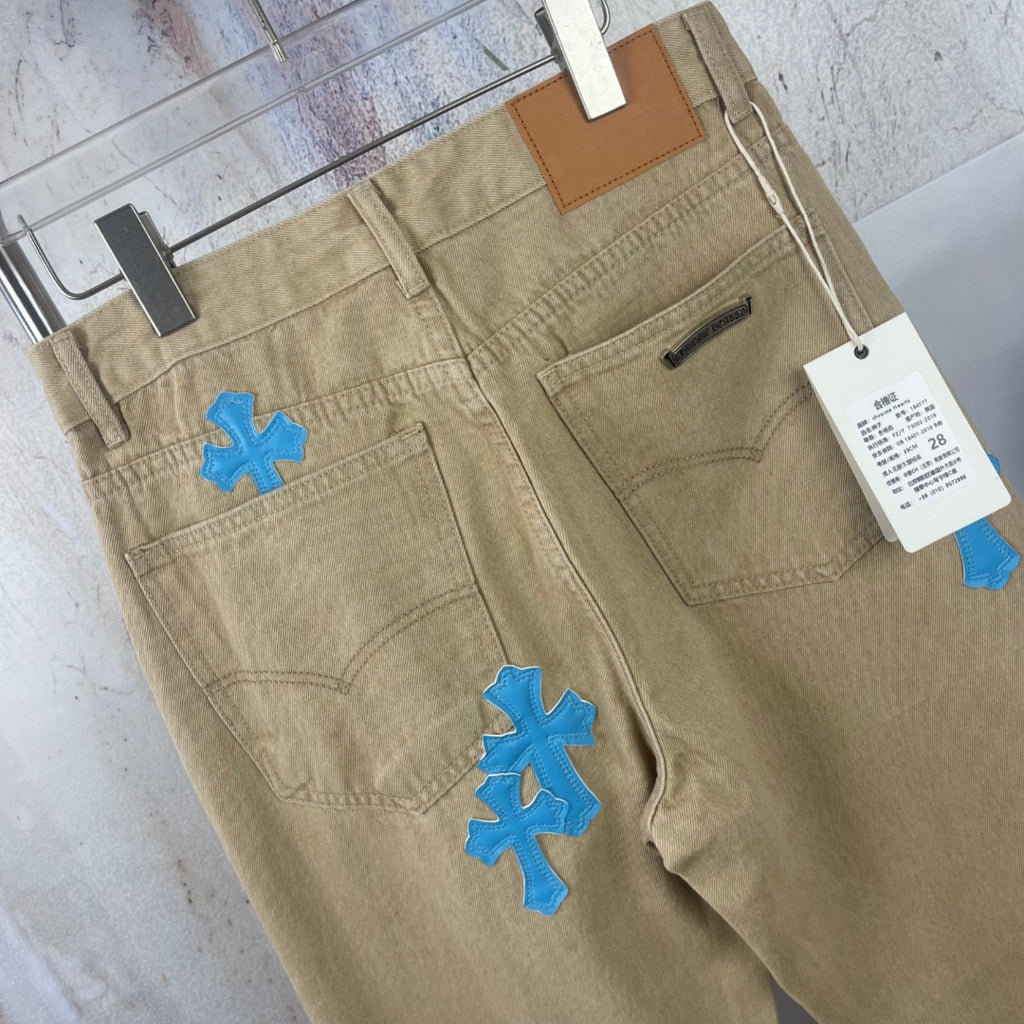 Beige pants front view with blue cross-heart patches, coin pocket and side zip