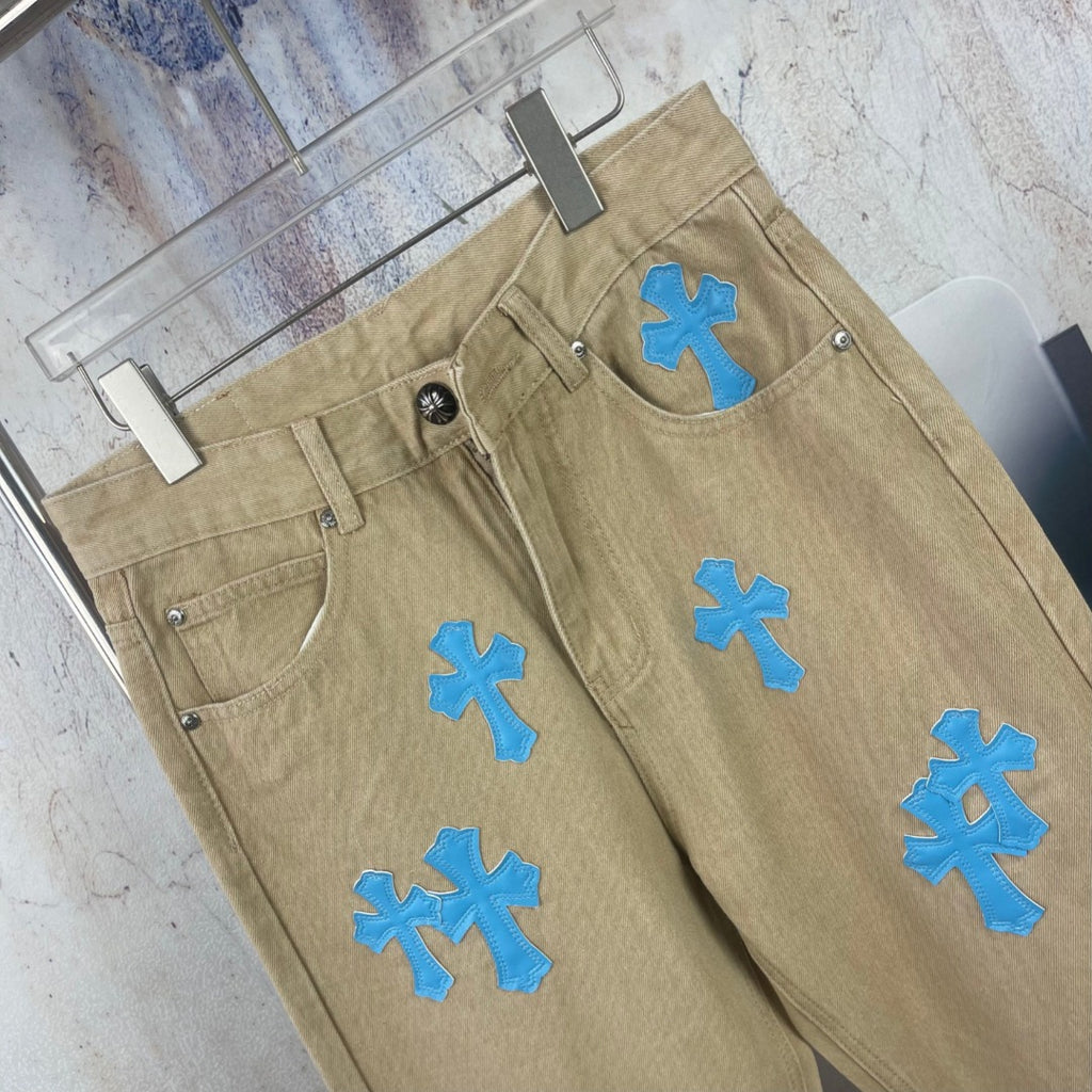 Tan straight-leg pants with blue cross-heart applique on front and back pockets